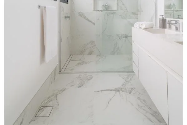 Nos banheiros, os ralos invisíveis são executados nos sistemas linear e square, cada um com suas minúcias que complementam a sobriedade que entregam aos ambientes. Nesse projeto, a arquiteta Isabella Nalon adotou o ralo, também considerado como invisível, no box e do lado de fora | Foto: Julia Herman 