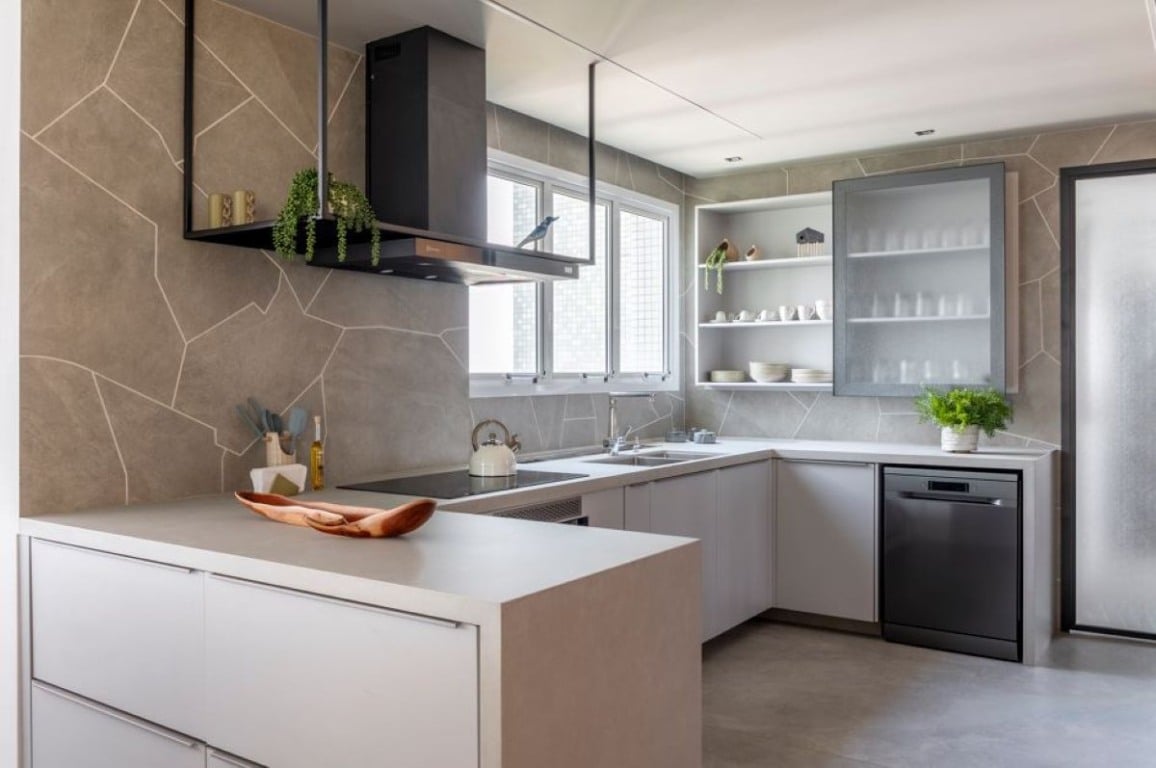 No projeto dessa cozinha, o arquiteto Raphael Wittmann adornou as paredes com o mesmo porcelanato do piso, mas de uma outra maneira: ousou a produzir recortes orgânicos, realizados na obra, para entregar um toque moderno e natural ao ambiente | Projeto Rawi Arquitetura + Design | Foto: Rafael Renzo