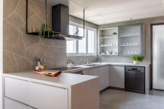 No projeto dessa cozinha, o arquiteto Raphael Wittmann adornou as paredes com o mesmo porcelanato do piso, mas de uma outra maneira: ousou a produzir recortes orgânicos, realizados na obra, para entregar um toque moderno e natural ao ambiente | Projeto Rawi Arquitetura + Design | Foto: Rafael Renzo