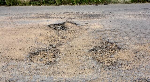 Buracos e mato tomam conta da Avenida Antônio Bernadino de Carvalho, no bairro Pedra do Descanso, na região do Vila Olímpia. (Foto: Ed Santos/Acorda Cidade)