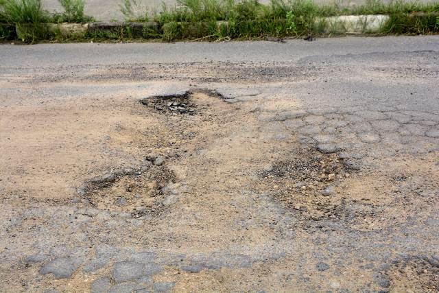 Buracos e mato tomam conta da Avenida Antônio Bernadino de Carvalho, no bairro Pedra do Descanso, na região do Vila Olímpia. (Foto: Ed Santos/Acorda Cidade)