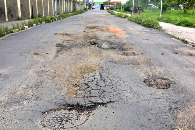 Buracos e mato tomam conta da Avenida Antônio Bernadino de Carvalho, no bairro Pedra do Descanso, na região do Vila Olímpia. (Foto: Ed Santos/Acorda Cidade)