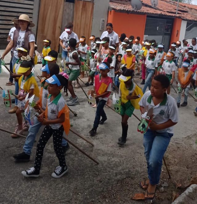 crianças desfilando com cavalinhos de pau