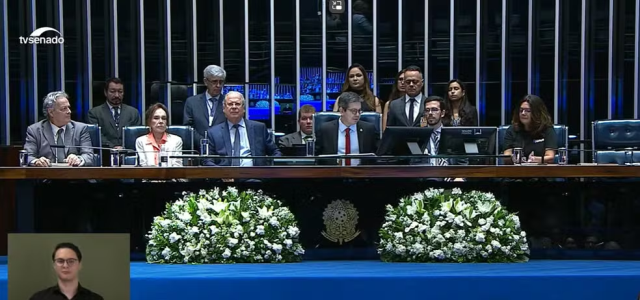 Ex-ministro José Dirceu (sentado, com terno azul escuro) participa de solenidade no Senado — Foto: TV Senado/Reprodução